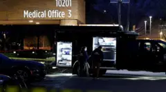 「Medical Office（医務室）」と書かれた建物の外にトラックが停まり、「FBI」と背に書かれたジャケットを着た2人が、開いた荷物部分の前に立っている。棚状になった荷物スペースは白いライトで照らされ、さまざまな大きさの容器がつまれている。建物の前には警察の黄色い規制線が張られている