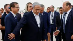 رئيس الوزراء الإسرائيلي بنيامين نتنياهو وهو يحاول إعاقة الرئيس الإسرائيلي إسحاق هرتسوغ عن التقدم أمامه، أثناء انتظار وصول الرئيس الأمريكي جو بايدن