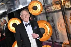 Tom Michell usando um terno preto com uma gravata borboleta