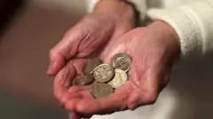У рукама старије жене метални новчићи