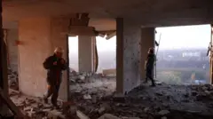 Два спасателя на разрушенном высоком этаже здания.