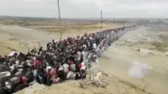 Fila congestionada de pessoas em um corredor cercado próximo a um centro da GHF em Gaza