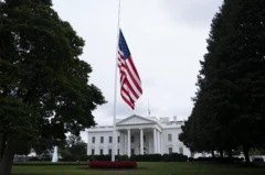 Bandeira dos EUA a meio-mastro, com Casa Branca vita ao fundo