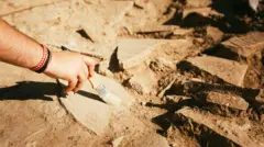Zbliżenie dłoni kobiety używającej pędzla do odkurzania ceramiki na stanowisku archeologicznym
