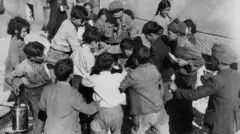 Crianças se reúnem em volta de uma panela de comida