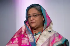JULY 22: Sheikh Hasina, the then-Prime Minister of Bangladesh, speaks at a summit in Walworth Academy in London. She is wearing a bright pink, blue and white scarf on her head and spectacles.
