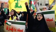 Des partisans du Hezbollah lèvent le poing en portant des drapeaux palestiniens et du Hezbollah lors d'un rassemblement de solidarité avec les Palestiniens de la bande de Gaza dans le sud de Beyrouth, au Liban, le 13 octobre 2023.