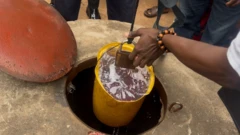 Ẹnikan to duro laarin ọpọ ero, n fa epo disu lati inu kanga ni Yemetu n'Ibadan pẹlu dooro ifami awọ olomi ọsan