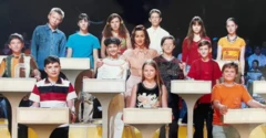 Con una camiseta roja, Oleksandr Ivanov es uno de los 13 niños y niñas que están de pie, en tres filas, detrás de atriles blancos, frente al público de un estudio de televisión sentado en gradas. Una presentadora adulta, vestida con una blusa color melocotón, está de pie en el centro, abrazando a dos de los niños.
