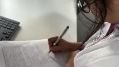 কাগজে স্বাক্ষর করছেন একজন নারী
