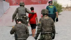 Soldados y un agente de la Guardia Civil acompañan a un menor en Ceuta