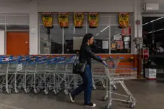Um cliente empurra um carrinho em um supermercado.
