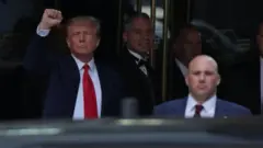 Trump erguendo o braço em sinal de vitória 