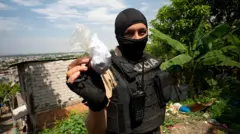 Policial de balaclava e colete protetor mostra um saco plástico cheio de um pó branco