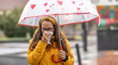 ဆောင်းဦး မိုးရွာတဲ့နေ့မှာ နှာရည်ယို၊ နှာချေနေတာကို လက်ကိုင်ပုဝါနဲ့ သုတ်နေတဲ့ အမျိုးသမီး