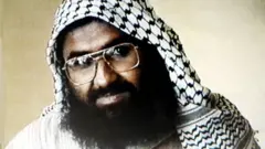 مسعود اظهر در حال نگاه کردن به دوربین در عکسی که در سپتامبر ۱۹۹۹ در زندان کوت بهاول جامو گرفته شده است. او عینک به چشم دارد و شالی سیاه و سفید بر سر انداخته است. ریشی بلند و سیاه دارد. پس‌زمینه عکس به رنگ کرم است.