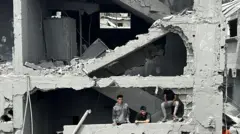 مجموعة من الشبان يقفون بين أنقاض مبنى مدمر جزئياً في حي الشجاعية شرقي مدينة غزة.
