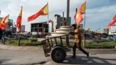 የኢትዮጵያ እና ትግራይ ክልል ባንዲራዎች በተሰቀሉበት አደባባይ ጋሪ እየገፋ የሚያልፍ ወጣት