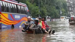ঢাকার একটি জলাবদ্ধ সড়ক দিয়ে রিকশা টানছেন চালকেরা
