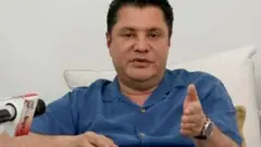 Rostam Aziz, wearing a blue shirt, speaking at a press conference