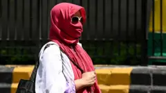 दिल्ली में तेज़ धूप और गर्मी से परेशान लोग