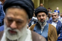 Modžtaba Hamenei u smeđem ogrtaču i crnom turbanu gleda u kameru, ima naočale