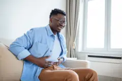 Homme tenant son ventre avec une expression douloureuse