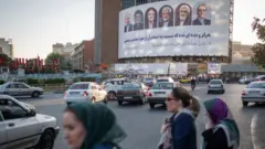 زنان عابر پیاده در برابر بیلبورد انتخاباتی