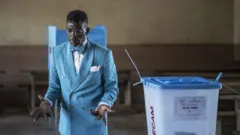 Wani mutum bayan kaɗa ƙuri'a a rumfar zaɓe a birni  Yaounde na Kamaru, a ranar 12 ga watan Oktoban 2025
