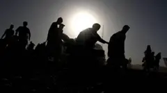 تصویر شماری از مهاجرانی که ازپاکستان به افغانستان اخراج شده اند. تصویر تاریک است چهره‌های شان معلوم نمی‌شود اما مهاجران در یک قطار همه به سمت راست تصویر درحرکت هستند. 