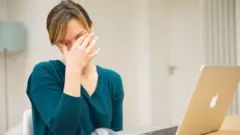 سيدة متعبة ومرهقة أمامها جهاز حاسوب محمول (لابتوب).