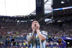 Messi con las manos sobre su rostro, y una tribuna del estadio repleta de aficionados detrás.