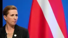 A primeira-ministra da Dinamarca, Mette Frederiksen, em frente à bandeira do país