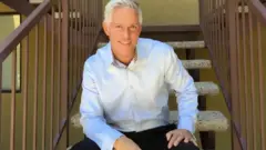 Paul sentado em uma cadeira olhando para a câmera