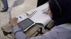 سيدة في لجنة الانتخابات في العراق تتحقق من هوية مقترع.