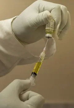 Mão colocando líquido em uma seringa