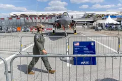 Uma pessoa vestida com traje de piloto caminha em frente a um F-35 A Lightning II de nova geração, fabricado nos Estados Unidos, exposto durante o primeiro dia da 55ª edição do Salão Internacional de Aeronáutica de Paris, no Aeroporto de Paris-Le Bourget, próximo a Paris, França, em 16 de junho de 2025