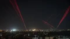 gece lübnan'ı yukarıdan gösteren bir fotoğraf. uzun pozlama ile kurşunların gökyüzünde bıraktığı kırmızı izler fotoğraflanmış. 