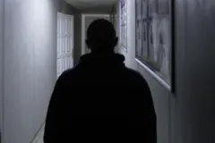 Vista trasera de la mitad superior de Vlad, en silueta, en un pasillo mal iluminado del centro de detención de Rivne. Tiene la cabeza rapada.