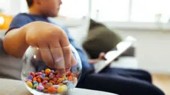 Menino comendo doce sentado no sofá com um tablet