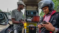 A worker fills petrol in an motorbike at a fuel station 