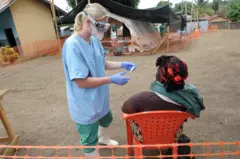 Un infirmier de l'organisation d'aide médicale "Médecins sans frontières" ("Medecin sans frontieres") examine un patient dans la zone d'accueil d'un centre pour victimes du virus Ebola à Guekedou, le 1er avril 2014. 