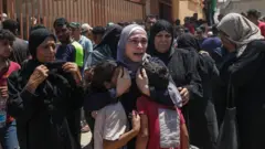 فلسطينية تحضن طفلين بعد غارة إسرائيلية على منطقة المواصي في 13 يوليو/ تموز 2024