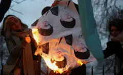 Jovem sorri ao ver fotos de Khamenei queimando