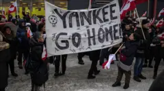 две жене држе транспарент 'Јенки (Американци), идите кући' на демонстрацијама у Нуку, главном граду Гренланда