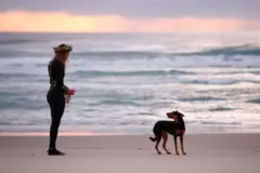 Ellidy Pullin com seu cachorro ao entardecer, de frente para o mar