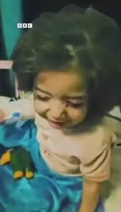 ඇඳක් මත කුඩා දැරියක් සිටින අයුරු පෙනේ.