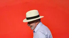 O presidente Lula, de perfil, em um fundo vermelho