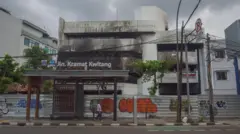 Pejalan kaki melintas di samping gedung ACC Kwitang yang ditutup seng di Senen, Jakarta Pusat, Minggu (2/11/2025). 