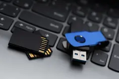 Um par de cartões SD e um pendrive azul sobre o teclado de um laptop